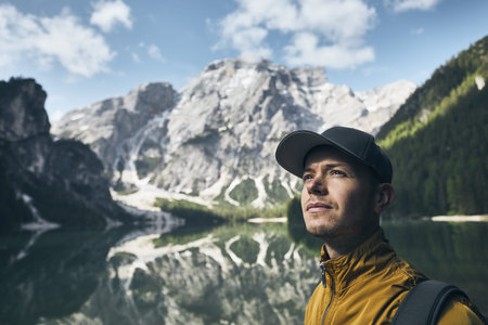 Young man (tourist) in nature. Mountains refelection in Lake Braies, Italy.の写真素材