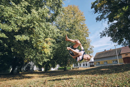 Boy practicing free runnuing in public park and jumping upside down.