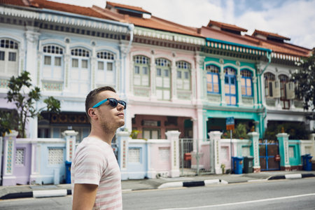 Tourist with sunglasses walking throught old street in Singapore. Colorful houses with combined Malay, Chinese, Indian and western architecture and culture.の写真素材