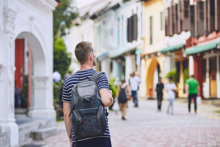Traveler in city. Young man with backpack admiring architecture of old houses in Singapore.の写真素材