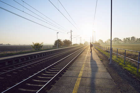 Alone young man with backpack waiting for train at railroad station at sunrise.の写真素材