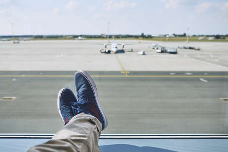 Man waiting at airport. Personal perspective of traveler from window to taxiways and runway.の写真素材