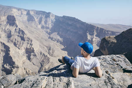 Young tourist resting on the edge of cliff. Jebel Akhdar, Grand Canyon of Oman.の写真素材
