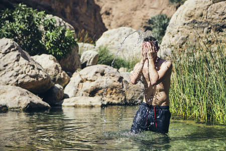 Young man splashing water on face. Refreshing in Wadi Shab, Sultanate of Oman.の写真素材