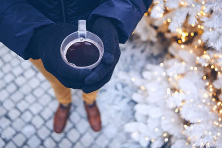 Man holding cup of mulled wine against illuminated christmas tree.  Munich, Germany.の写真素材
