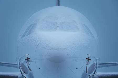 Winter morning at airport. Airplane covered by snow waiting for deicing.の写真素材