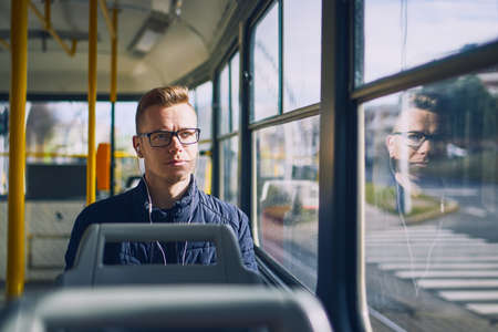 Young man listening music in tram. Travel by public transportation.の写真素材