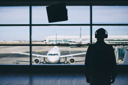 Passenger with headphones. Young man walking through airport terminal to airplane.の写真素材