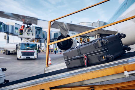 Preparations before flight. Loading luggage into airplane against refueling of airplane at airport. Travel and industry concepts.の写真素材