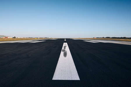 Surface level of airport runway with road marking against clear sky.の写真素材