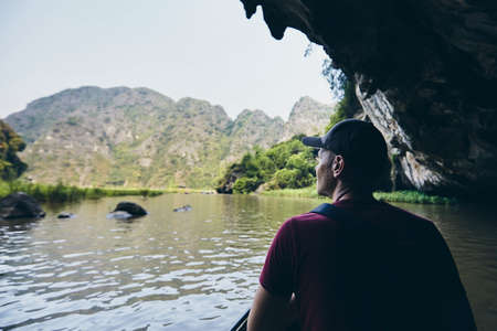 Man on boat floating through to cave. Themes adventure, exploration and travel. Ninh Binh province, Vietnamの写真素材