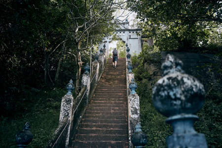 Young tourist climbs up stairs to gate of ancient temple near Tangalle. Mulkirigala, Sri Lanka.の写真素材