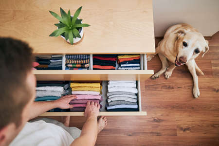 Organizing and cleaning home. Man preparing orderly folded t-shirts in drawer.の写真素材