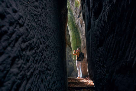 Photographer in narrow footpath looking up to rock formations. Hruba Skala in Bohemian Paradise, Czech Republicの写真素材