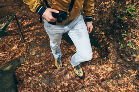 Young man during trip. Low section of photographer with camera walking on footpath.