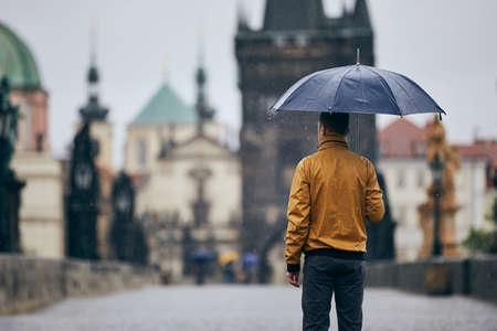 Lonely man with umbrella in heavy rain on empty Charles Bridge. Prague Czech Republicの写真素材