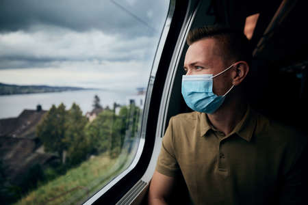 Man wearing face mask inside train. Themes new normal, coronavirus and personal protection in public transportation.の写真素材
