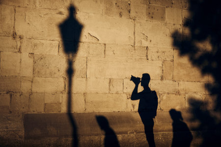 Shadow of photographer on stone wall. Young man photographing of old street at sunset. Zurich, Switzerland.の写真素材