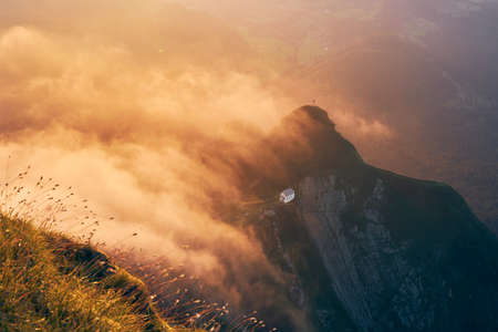 Swiss landscape at beautiful sunset. Chapel on mountain in the middle of clouds. View from Mount Pilatus, Lucerne, Switzerlandの写真素材