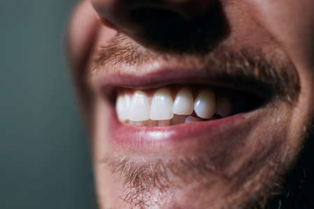Toothy smile of young man. Close-up view of white teeth.の写真素材
