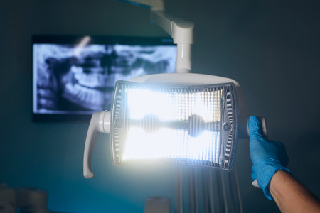 Modern dental surgery. Dentist adjusting lamp against x-ray of teeth in dental clinic.の写真素材