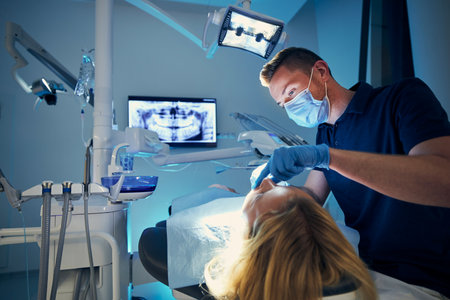 Dentist examining patient with dental equipments against modern dental surgery with x-ray.の写真素材