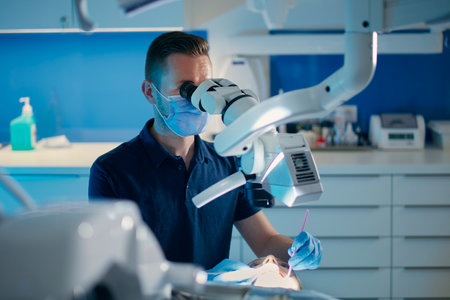 Dentist examining teeth of young patient via microscope in modern dental surgery.の写真素材