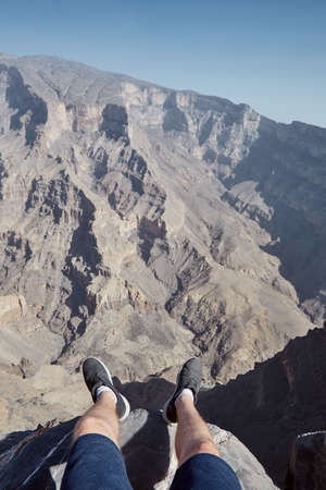 Young man resting at the edge of cliff. Personal stunning view with canyon, Jebel Shams in Omanの写真素材