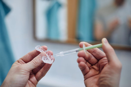 Young man preparing silicon tray for teeth whitening and bleaching gel syringe. Themes dental health, care and beauty.の写真素材