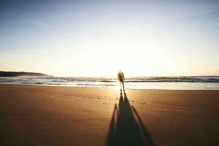 Silhouette of lonely person on empty beach. Rear view of man during watching sunrise. Sandy coast of Sri lanka.の写真素材