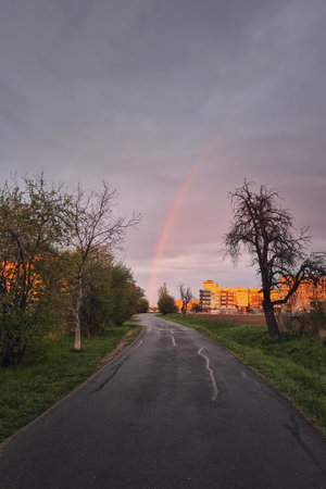 Road to city against rainbow above buildings during spring rain. Prague, Czech Republicの写真素材
