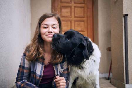 Portrait of happy teenager girl sitting with her Czech mountain dog against against door of house.の写真素材