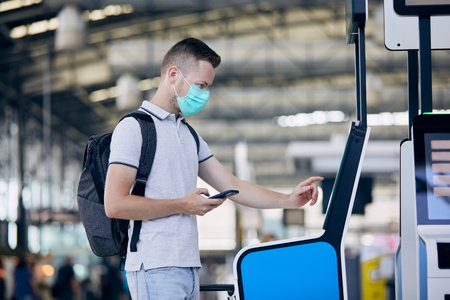 Man using self service check-in machine. Passenger scanning ticket on smart phone at airport...
