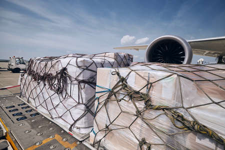 Preparation before flight. Loading of cargo containers against jet engine of freight airplane.の写真素材