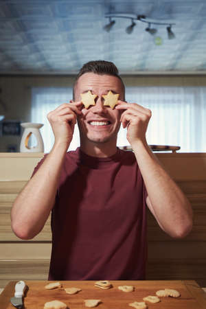 Funny portrait of young man during baking Christmas sweets at home kitchen.の写真素材