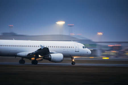Airplane during take off on airport runway at night. Plane in blurred motion at night.の写真素材