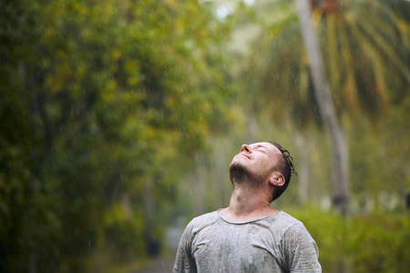 Portrait of drenched man with eyes closed enjoying heavy rain in nature.の写真素材