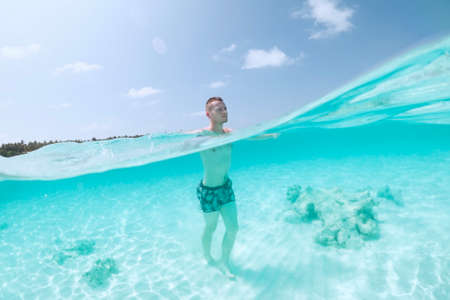 Man walking on sand seabed of beautiful turquoise sea. Tourist enjoying beach holiday.の写真素材