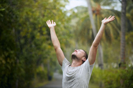 Portrait of drenched man with eyes closed enjoying heavy rain in nature.の写真素材