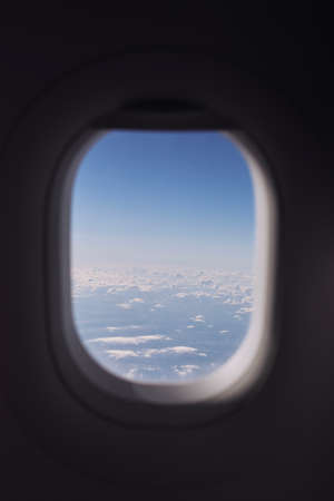 Window of airplane during flight above clouds on beautiful sunny day.の写真素材