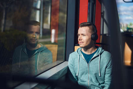 Man listening music in wireless headphones while commuting by public transportation.の写真素材
