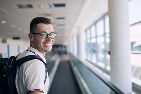 Portrait of smiling traveler at airport. Happy man looking at camera before his travel by airplane.