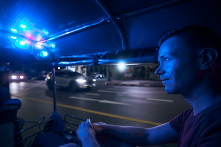 Man enjoying tuk tuk ride at night. Portrait of tourist in taxi. Bangkok, Thailandの写真素材