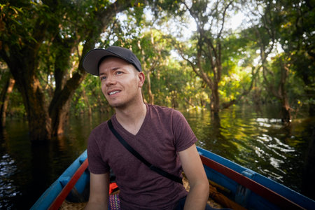 Man on boat exploring forest on lake near Siem Reap in Cambodia.の写真素材