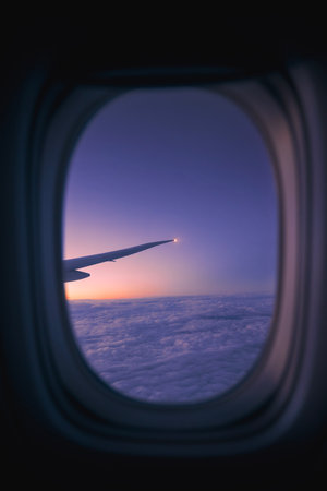 View from window of airplane during flight above clouds at dawn. Selective focus on aircraft wing.の写真素材