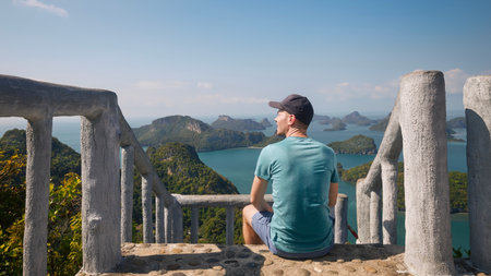 Man sitting on staircase on hill and looking at sea with group beautiful tropical islands. Ang Thong National Marine Park near Koh Samui in Thailand.の写真素材