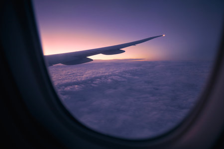 View from window of airplane during flight above clouds at dawn. Selective focus on aircraft wing.の写真素材