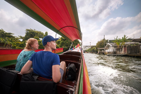 Senior woman with her adult son enjoying together trip on traditional boat in Bangkok, Thailand.の写真素材