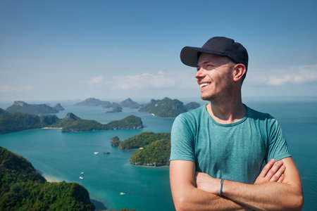 Portrait of laughing man on hill against group of tropical islands in sea, Thailandの写真素材