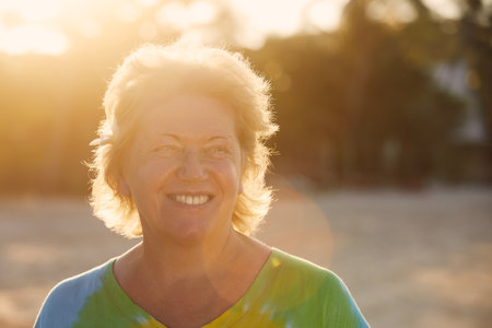 Portrait of happy woman on beach in tropical destination at sunset. Senior tourist in tropical destination.の写真素材